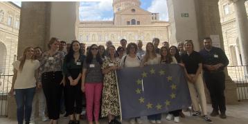 Group photo of PROXIMITIES partners standing holding EU flag with PROXIMITIES logo in corner